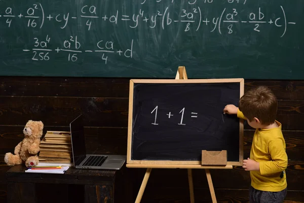 教育コンセプトです。小さな男の子は、黒板上の方程式を解きます。スマートな子供のための就学前教育 — ストック写真