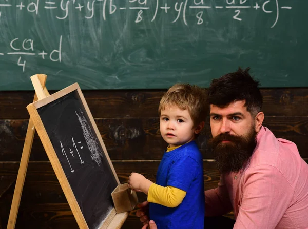 Vorschulkind und seine Lehrerin im Klassenzimmer. Vater hilft seinem kleinen Jungen bei Mathe. Papa umarmt sein Kind — Stockfoto