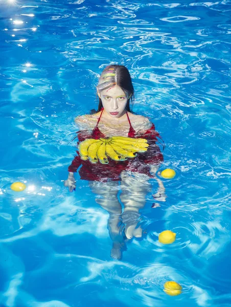 Vitamina em banana em menina que se senta perto de água. mulher com frutas tropicais na piscina. Mulher relaxar na piscina spa. Férias de verão e viagens ao oceano. Alimentação e alimentos orgânicos saudáveis, vegetarianos . — Fotografia de Stock