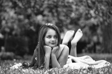 Yaprakları yeşil çimenlerin üzerinde küçük kız