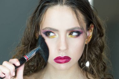 Güzellik kız makyaj fırça ile. Kahverengi gözlü esmer kadın için parlak tatil makyaj. Güzel yüz ve makyaj. Mükemmel cilt. Makyaj uygulamak