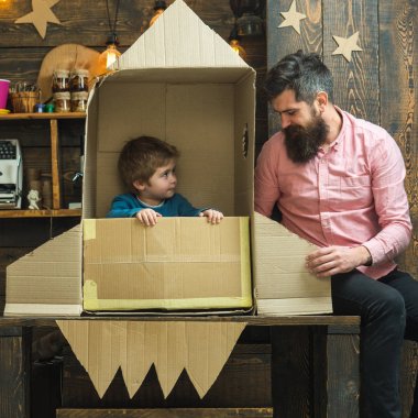 Baba, baba, küçük kozmonot ile çocuk oyun karton kutudan yapılan roket oturup. Çocuk mutlu oturmak karton el roket yapımı. Roket fırlatma kavramı. Çocuk şirin çocuk oyun kozmonot, astronot.