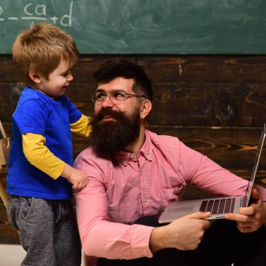 Gülümseyen Baba oğlunu bilgisayar becerilerinin öğretimi. Baba ve oğul birbirine bakarak. Oturan babası boynumdan sarılmayı çocuk ayakta.