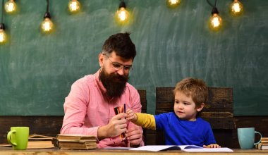 Anaokulu resim dersinde. Öğretmen ve bir resim çizim çocuk. Babası holding yığın renkli kalemler.