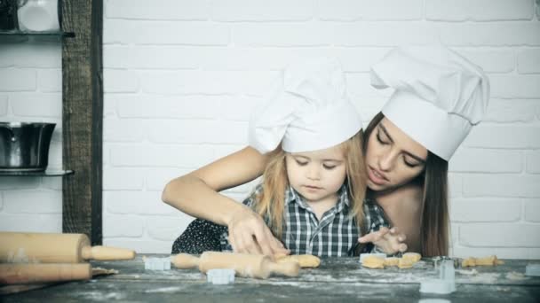 幸せな家族は一緒にパン屋を準備しています 母親と子供の娘はクッキーを調理し キッチンで楽しんでいます 自家製の食べ物と小さなヘルパー — ストック動画
