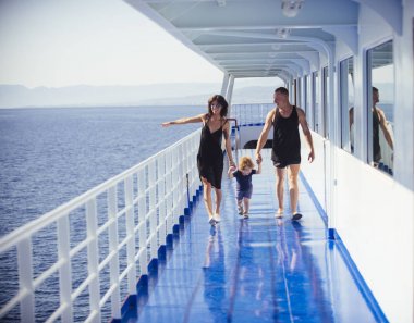 Yaz tatil tatlı oğluyla mutlu bir aile. Üzerinde seyahat aile cruise gemi güneşli günde. Aile dinlenme kavramı. Baba, anne ve çocuk ile arka plan üzerinde deniz cruise liner güvertede yürümek.