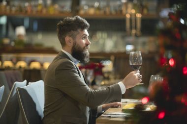 Restoranda iyi vakit. Kırmızı şarap ile cam tutarak ve restoranda gülümseyen yakışıklı delikanlı