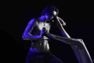 Moda kavramı. Çift soyunma moda çekim. Seksi bir adam bacak moda yüksek topuklu ayakkabı ile tutun. Kadın ayakkabı, siyah arka plan dışı pırıl pırıl boya alır adam çıplak gövde ile kaplı.