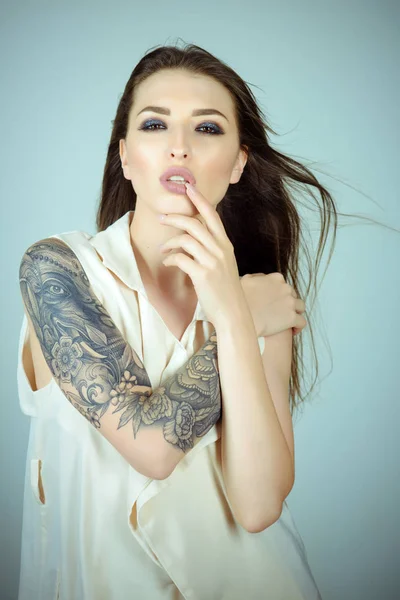 Skincare, body art. Sensual woman with tattoo painting, fashion. Woman with long brunette hair, hairstyle, beauty, salon. Tattoo, art, design, painting, draw, culture. Fashion, beauty, look, makeup.