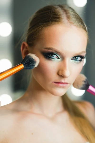 Cara de maquillaje chica con cepillos de polvo en el salón de belleza. Piel de niña, cuidado de la piel, cosméticos . — Foto de Stock