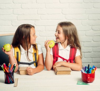 Geri okul ve evde eğitim için. Küçük kızları öğle tatilinde elma yerim. Kız okul zamanı. Dostluk bilgi gün sınıfta küçük kız kardeş. Mutlu okul çocukları derste, Eylül 1