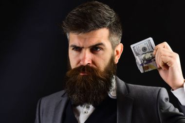 İşadamı, erkekte sakal ve bıyık üzerinde ciddi bir yüz ile formal giyim dolar dışında para kazandınız rulo tutar. Kar kavramı. Klasik takım, işadamı, siyah arka plan kapatmak, alanı Kopyala.