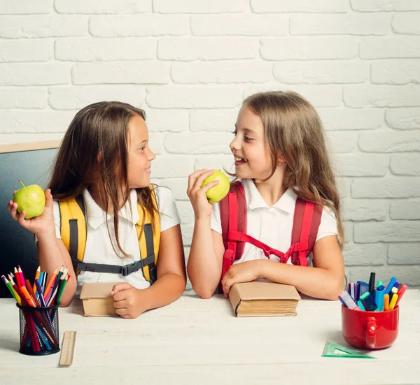 Zurück zur Schule und zum Schulbesuch. Kleine Mädchen essen in der Mittagspause Apfel. Schulzeit der Mädchen. Freundschaft kleiner Schwestern im Klassenzimmer beim Wissenstag. glückliche Schulkinder beim Unterricht im September 1 — Stockfoto