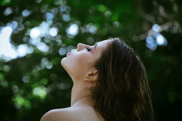 Hårvård, terapi och behandling. Kvinna med krullig frisyr och bar axel sommardag. Kvinna med lång brunett hår på naturen. Flicka med makeup ansikte, skönhet. Modell med glamour look — Stockfoto