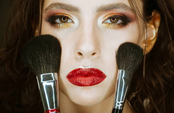 Chica con cepillos de maquillaje aplicar polvo en la cara, cosméticos. Chica con maquillaje de arte y labios rojos . — Foto de Stock