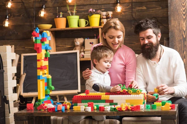家庭在家里玩构造函数。有胡子的父亲帮忙用积木、塑料块筑墙。母亲和可爱的儿子学步的孩子玩构造函数。家庭时间概念. — 图库照片