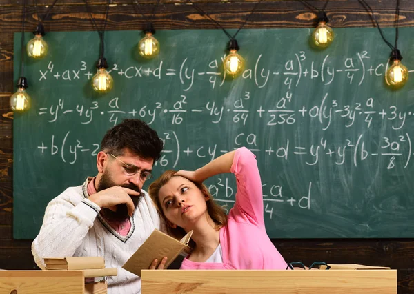 Universidad y concepto de educación. Estudiante escuchando profesor barbudo, profesor, profesor. Científico leyendo, sostiene el libro, mientras que la chica se apoya en su hombro, cansado y aburrido, fondo de pizarra . — Foto de Stock