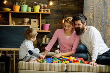 Baba, anne ve sevimli oğlu Oluşturucu tuğla ile oynamak. Şefkatli anne kavramı. Aile meşgul yüz üzerinde zaman harcamak birlikte odasında. Ebeveynler çalma plastik blokları ile çocuk, inşaat yapı.