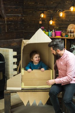 Çocuk mutlu oturmak karton el roket yapımı. Çocuk çocuk oyun kozmonot, astronot. Ebeveynlik kavramı. Baba, baba, küçük kozmonot ile çocuk oyun oturup karton kutudan yapılan roket.