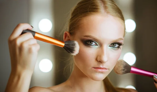 Makeup with powder brushes for young woman. Makeup model apply powder on skin