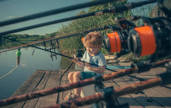 Bambino seduto sul molo del fiume con canna da pesca e pesca — Foto Stock