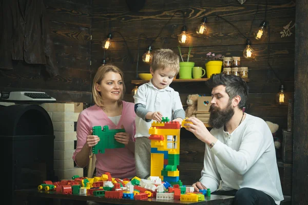 Vzdělávací hra koncept. Rodiče a jejich syn hrát s plastovými bloky. Máma pomáhá její syn a manžel stavební věž z barevných kostek — Stock fotografie