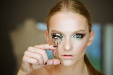 Kadın curl kirpiklere güzellik aracıyla, bak. Kadın kirpik kıvırıcı göz makyajı için kullanın. Kıvırcık uzun kirpiklerini, güzellik modeli. Glamour girl, Sima sahası için moda makyaj.