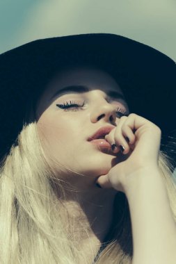 Yaz aylarında güneşli mavi gökyüzü arka plan kız. Moda kadın model poz açık. Güzellik ve moda vintage tarzı bak. Genç yüz makyaj. Güzel kız siyah zarif retro şapka ve kırmızı dudaklar.