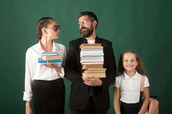 De vuelta a la escuela y a la educación en casa. Lección de literatura y lectura de libro de gramática. Tiempo escolar de hermanas y padre en la biblioteca. Jornada de educación en conocimiento. Maestro hombre y niñas celebrar libro pila en la escuela — Foto de Stock