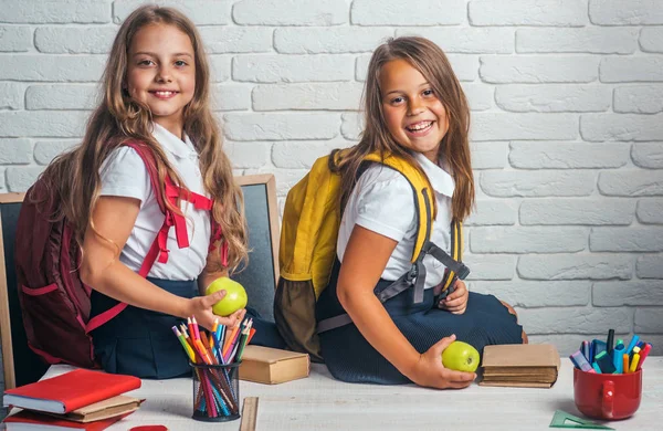 Χρόνου σχολείο των κοριτσιών. Φιλία από μικρές αδελφές στην τάξη κατά την ημέρα της γνώσης. Πίσω στο σχολείο και το σπίτι της σχολικής εκπαίδευσης. Μικρά κορίτσια τρώνε το μήλο στο μεσημεριανό διάλειμμα. Ευτυχισμένος σχολείο τα παιδιά στο μάθημα 1 Σεπτεμβρίου — Φωτογραφία Αρχείου