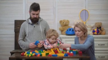 Genç aile oyun odası. Aile kavramı seviyorum. Anne, baba ve çocuk oyuncakları ile dışarı plastik blokları inşa. Anne ve oğlu gülümseyen, tuğla yapılar yapmak.