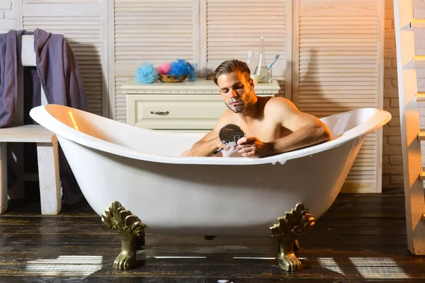 ひげを生やした男は浴室でお風呂でカミソリで剃る — ストック写真