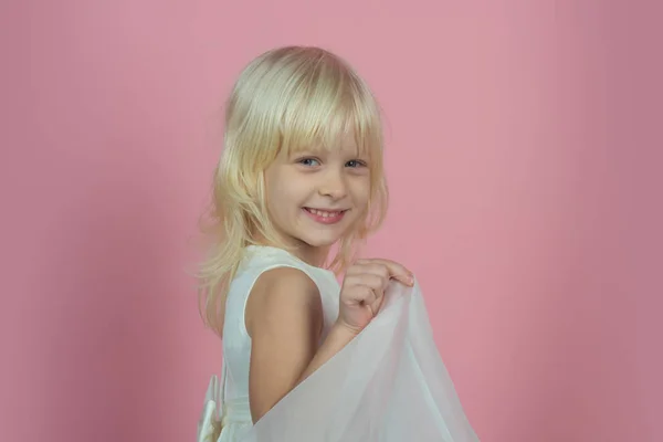 Porträtt av skrattande liten flicka håller kjol i vit klänning. Positiva emitions. Glada barn — Stockfoto
