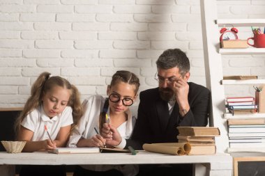 Geri okul ve evde eğitim için. Baba ile kız kız kardeş okul zamanı. Eğitim ve bilgi gün. Baba Çocuk evde çalışmaya yardımcı olur. Öğretmen adam ve küçük kızı okul ders yazma.