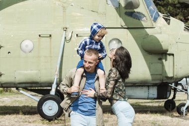 Anne ve baba ve çocuklarının Havacılık Müzesi havada yürüyüş. Mutlu aile zaman harcamak birlikte, gezi, helikopter veya uçak arka planda, güneşli bir gün. Yetiştirme ve geliştirme kavramı.