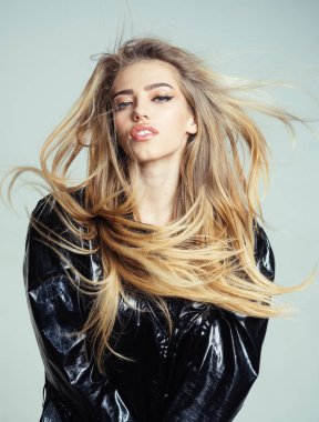 Bayan yağmurluk ya da yağmurluk poz seksi. Uzun saçlı kız siyah pelerin, gri arka plan giyer. Kadın ile rüya gibi yüz çekici şık pelerin veya mackintosh makyaj. Moda kavramı.