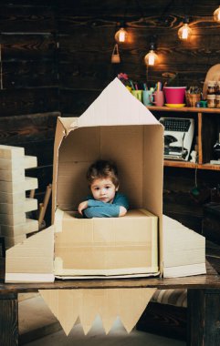 Çocuk karton el roket yapımı otur. Çocuk evde roket, roket karton kutudan yapılan küçük kozmonot oturmak ile oyun. Çocuk Çocuk oyun kozmonot, astronot. Çocukluk kavramı.