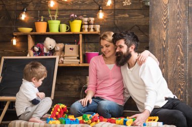 Anne ile Çocuk oyun plastik bloklar ile yapı inşaat. Baba, anne ve sevimli oğlu Oluşturucu tuğla ile oynamak. Ebeveynlik kavramı. Ebeveynler hugs, ebeveynlik zevk oynamak oğul izliyor,.
