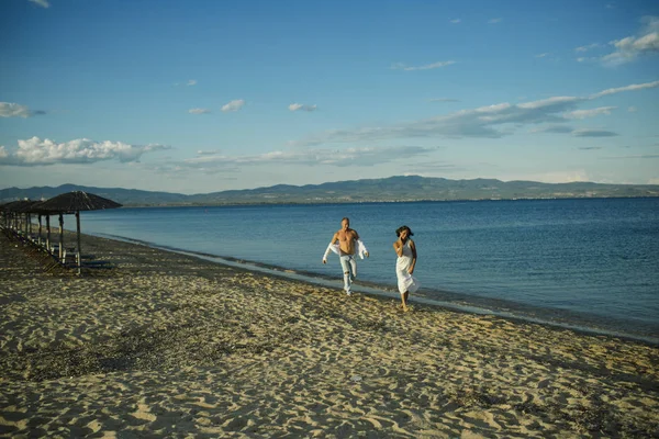 Homme et femme marchant, couple heureux en vacances. Couple amoureux courant sur la plage, au bord de la mer. Couple en amour marche, avoir du plaisir, fond de mer et skyline. Lune de miel, concept de mariage . — Photo