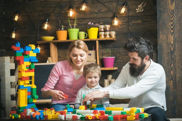 母亲和可爱的儿子玩构造砖 家庭在繁忙的面孔一起花费时间在娱乐室 教育游戏的概念 孩子与父母玩塑料积木 建造建筑 — 图库照片