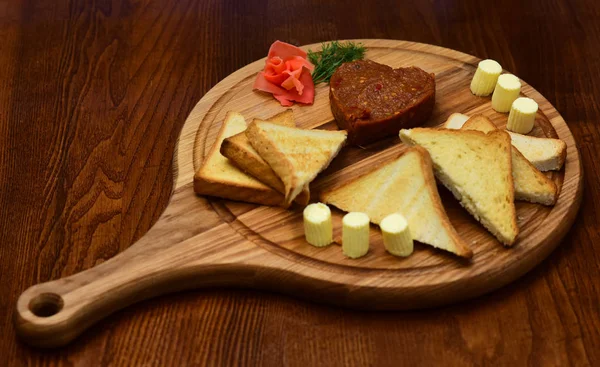 Tatar beefsteak served in shape of heart on round wooden board. Bread, toast and butter around beefsteak on board. Restaurant dish concept. Dish appetizing decorated with dill. — Stock Photo, Image