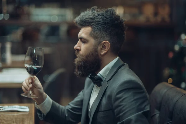 Date meeting of hipster awaiting in pub. Perfect wine. bar customer sit in cafe drinking alcohol. Businessman with long beard drink in cigar club. Bearded man rest in restaurant with wine glass.