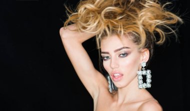 Kadın uzun saçlı ve şehvetli dudakları çekici görünüyor. Moda ve makyaj kavramı. Makyaj, ruj, maskara, şık seksi kızla giyer köpüklü büyük küpeler takı, koyu arka plan.