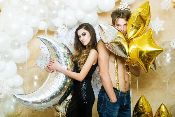 Mulher e homem sorriem com balões no Natal. Namorada e namorado sexy com balões de festa no ano novo. Casal apaixonado desfrutar de festa de férias. Feliz família comemorar o Natal e ano novo — Fotografia de Stock