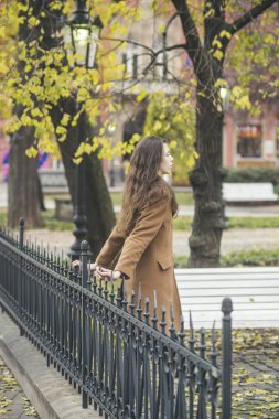 Güzellik, dating, kasaba, bekleyen, yürüyüş kavramı. Kız ceket açık havada duran, arkadan görünüm. Kadın erkek arkadaşıyla parkta bekler. Sonbahar hava ve rahat park. Romantik ruh hali ve uzun saçlı bayanla.