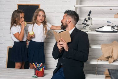Öğretmen adam kızlar yeme elma için hikaye okuyun. Kız ve baba Kitaplığı'nda okul zamanı. Bilgi gün eğitimde. Edebiyat ders ve okuma gramer kitabı. Geri okul ve ev okullaşma.