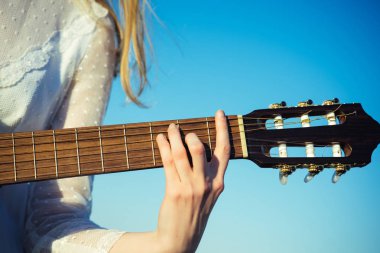 Eğlence, gitar dizeleri tıngırdatmaya parmak ile. Eğlence el yaylı çalgılar mavi gökyüzü üzerinde oynamak.