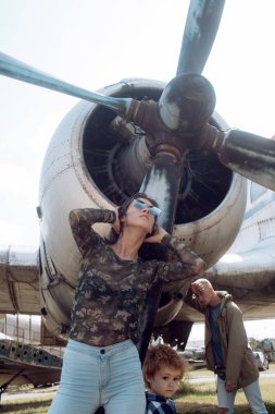 Aile zaman harcamak birlikte, gezi, arka plan, uçakta üzerinde güneşli bir gün. Aile Eğlence kavramı. Anne ve baba ve Havacılık Müzesi havada yürüyüş çocuk. Babam yürümekten yorgun görünüyor.