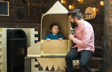 Baba, Baba, küçük kozmonot ile Çocuk oyun karton kutudan yapılan roket oturup. Çocuk mutlu oturmak karton el roket yapımı. Çocuk Çocuk oyun kozmonot, astronot. Ebeveynlik kavramı.