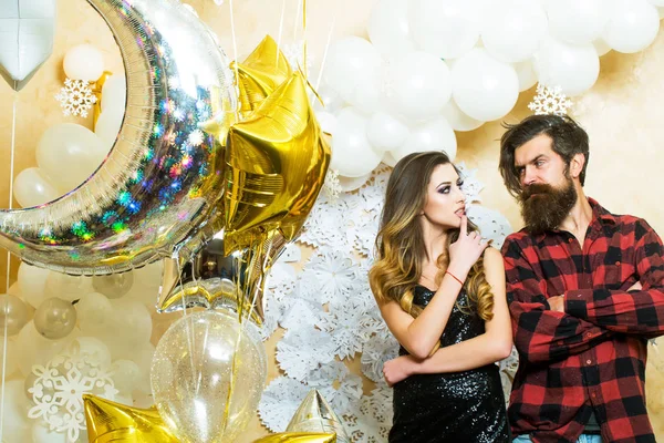 Hipster and woman on new year or xmas eve. Sensual woman and bearded man with party balloons, christmas. Couple in love enjoy holiday party celebration. Happy family celebrate christmas and new year.